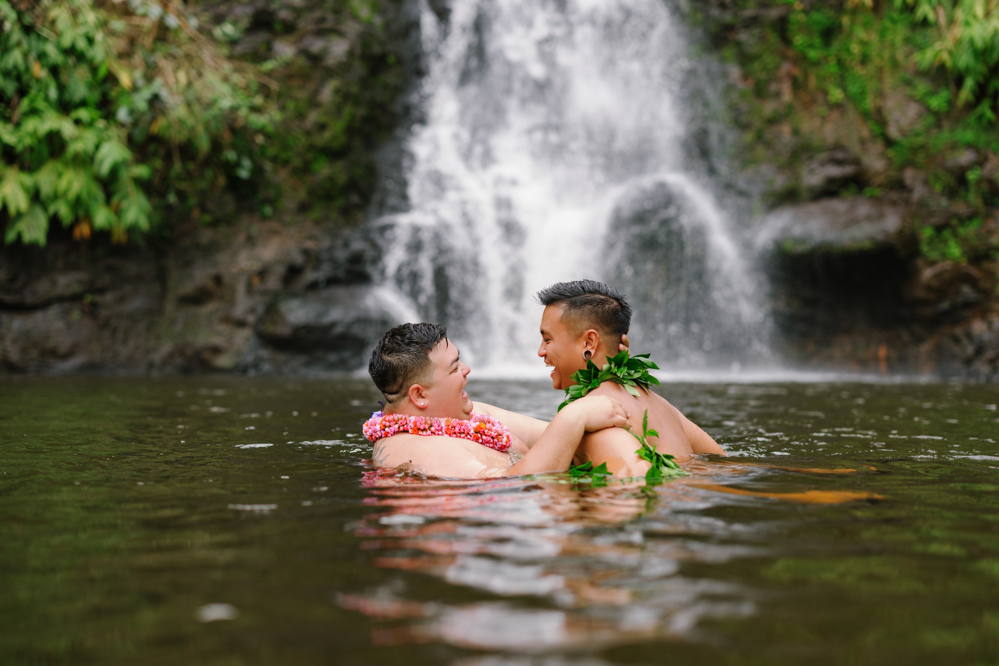 Tylor and Austin laughing together in a pool below a waterfall