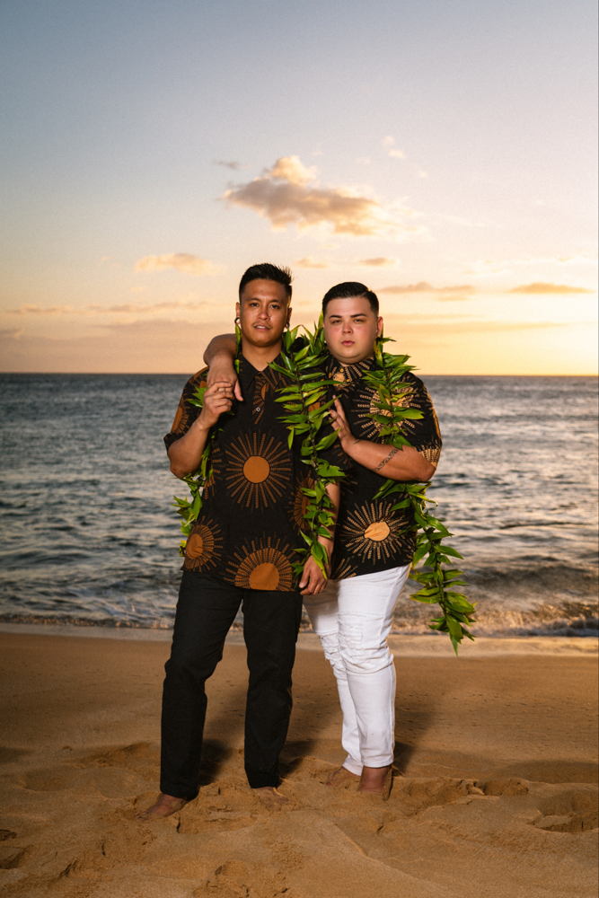 Tylor and Austin on the beach at sunset wearing lei